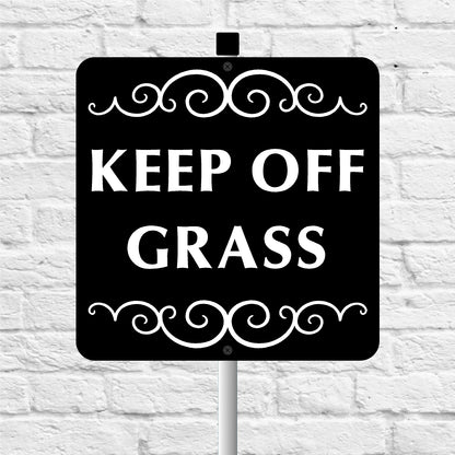 Black sign with 'KEEP OFF GRASS' text on a white brick wall background