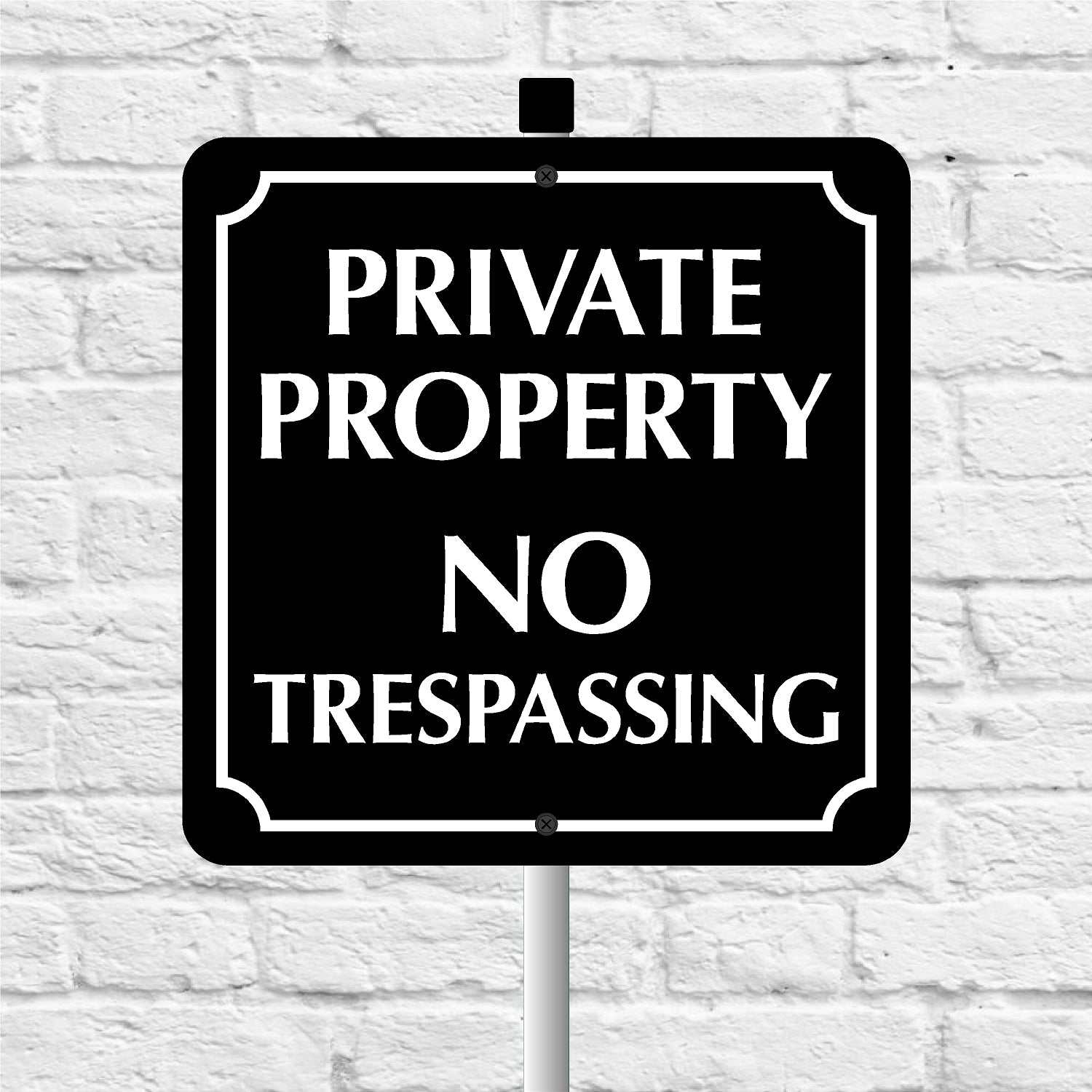 Black and white 'Private Property No Trespassing' sign against a white brick wall.