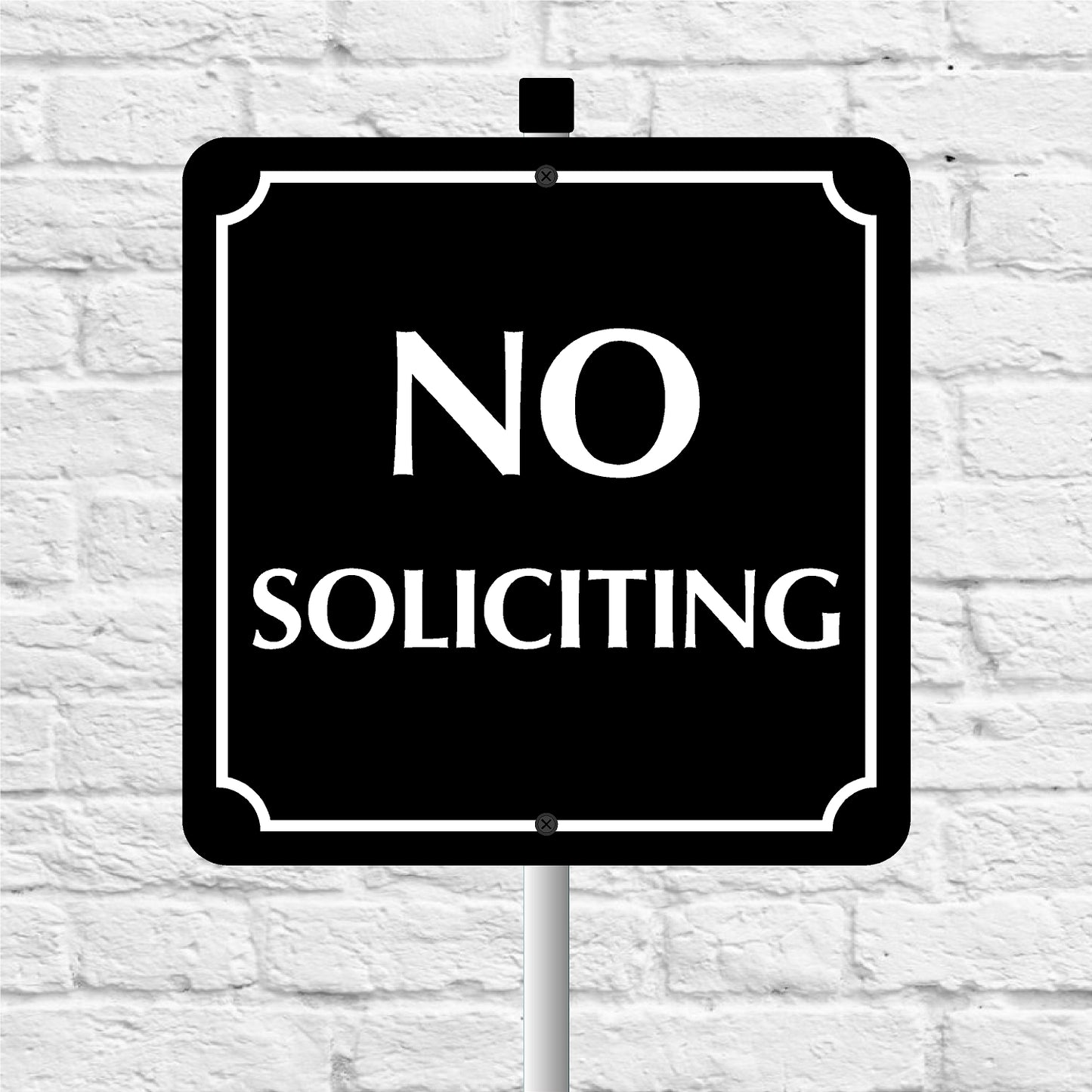 No Soliciting sign on a white brick wall