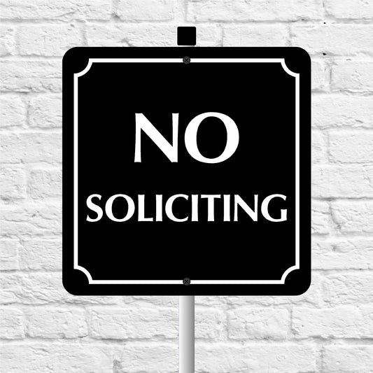 No Soliciting sign on a white brick wall