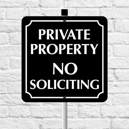 Black and white 'Private Property No Soliciting' sign against a light gray brick wall.
