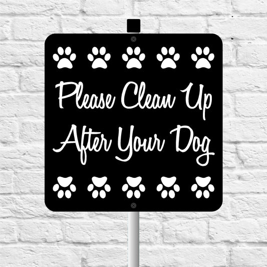 Sign with paw prints and text 'Please Clean Up After Your Dog' on a white brick background