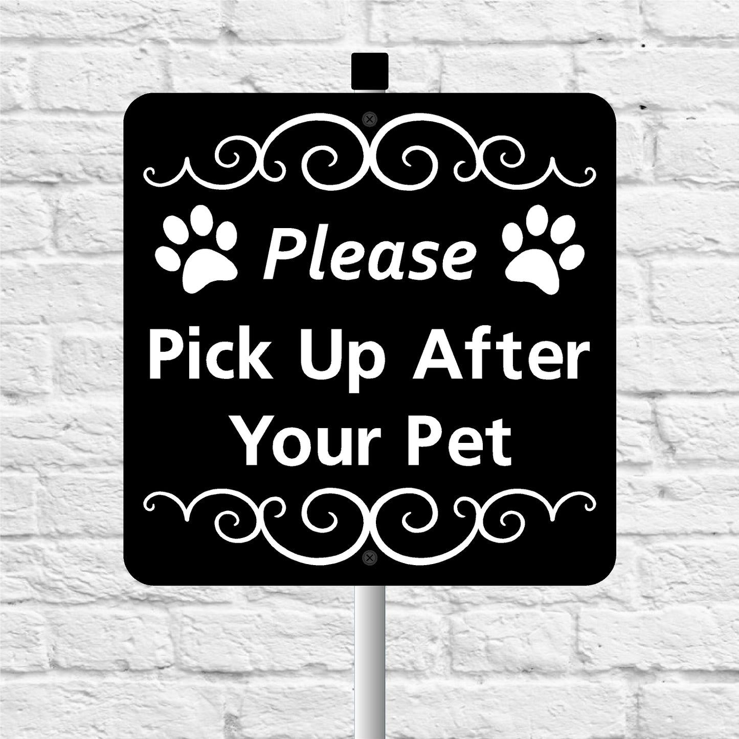 Black sign please pick up after your pet with white text and paw prints on a white brick wall background