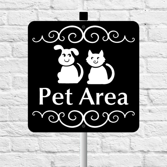 Black sign with white text and graphics of a dog and cat, indicating 'Pet Area', against a white brick wall background.