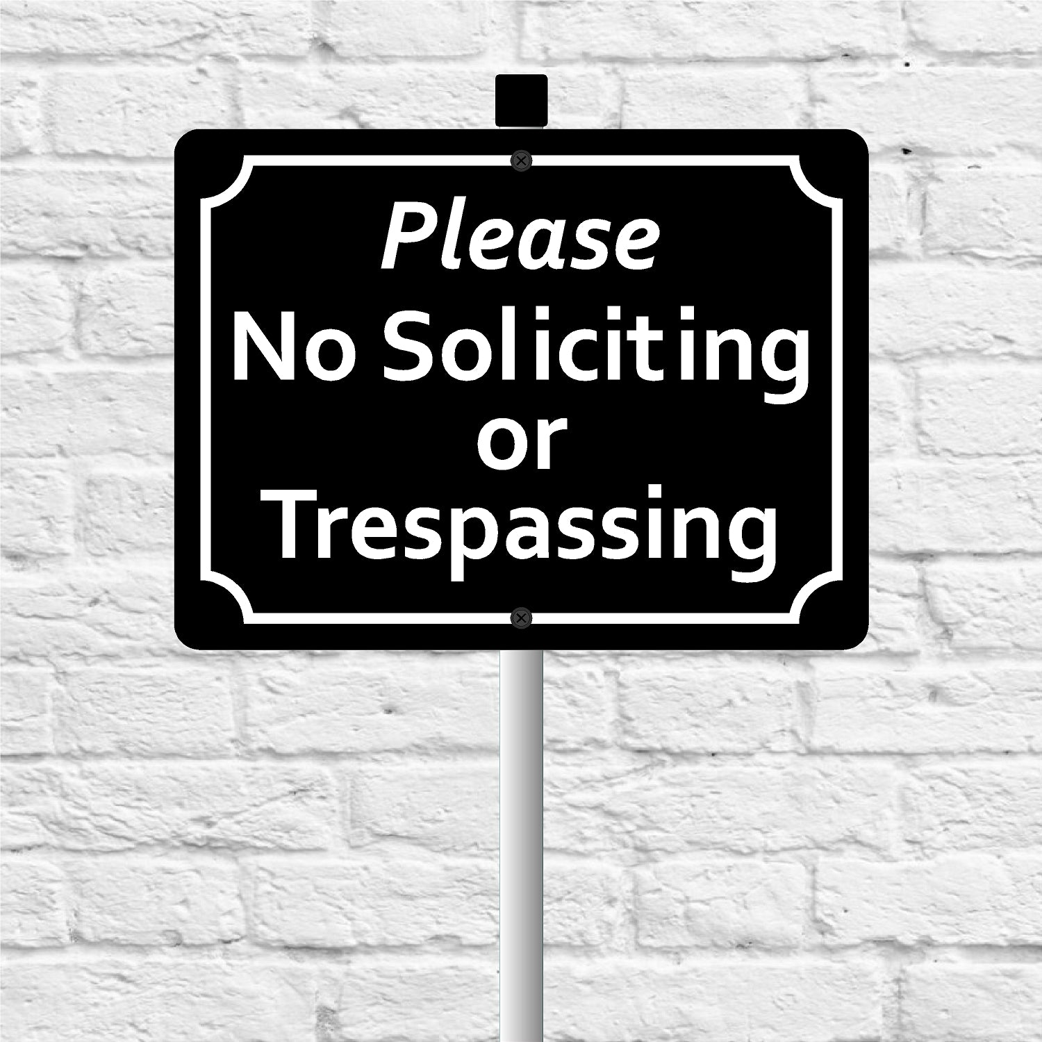Sign with 'Please No Soliciting or Trespassing' text against a white brick wall.