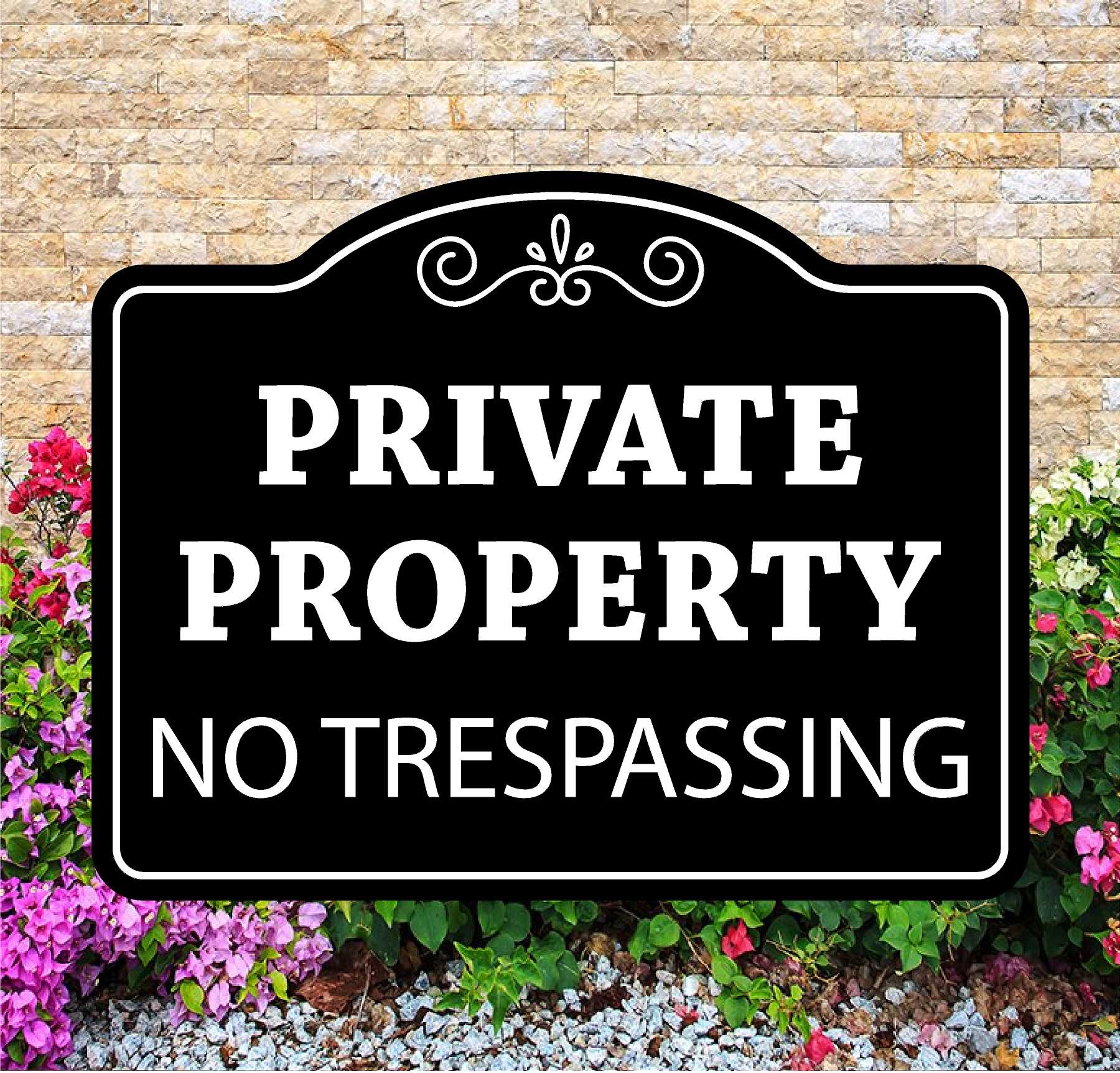 Black and white 'Private Property No Trespassing' sign in front of a stone wall and flowers.