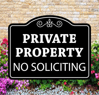Black and white 'Private Property No Soliciting' sign in front of a brick wall and flowers.
