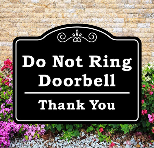 Black sign with 'Do Not Ring Doorbell Thank You' text against a brick wall and flower background