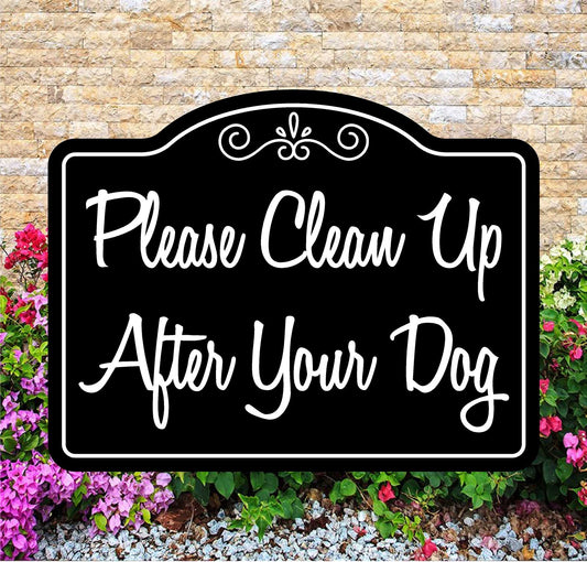 Decorative sign with 'Please Clean Up After Your Dog' text in front of a brick wall and flowers.