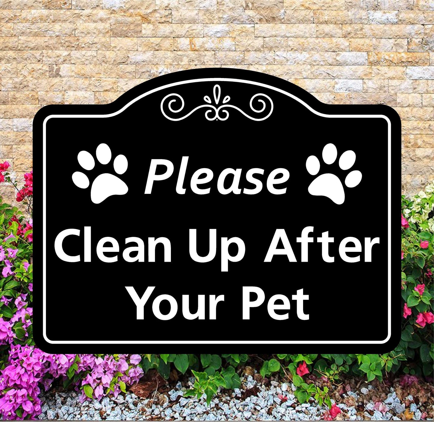 Decorative sign with paw prints and text 'Please Clean Up After Your Pet' against a stone wall and flower background.