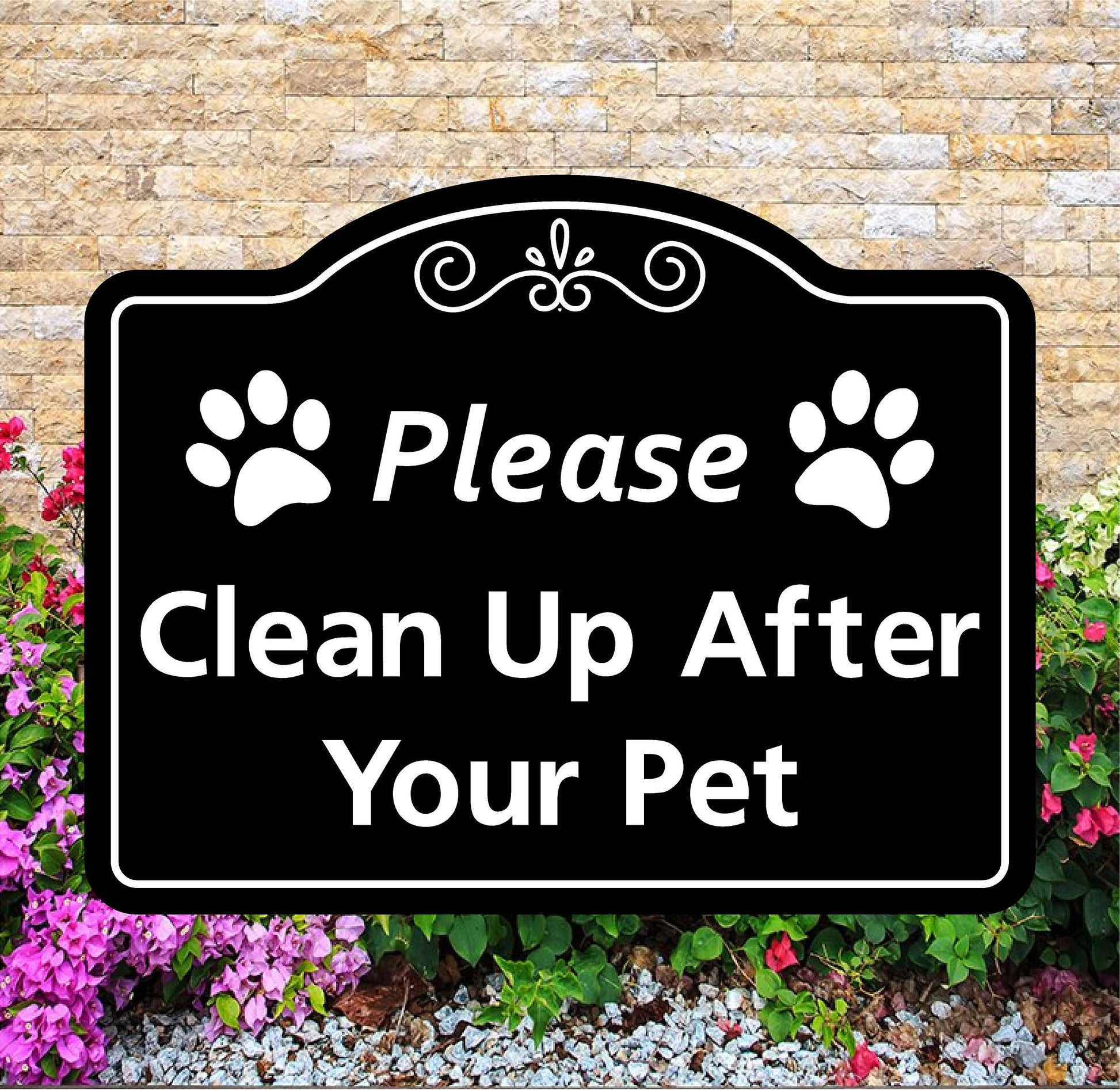 Decorative sign with paw prints and text 'Please Clean Up After Your Pet' against a stone wall and flower background.